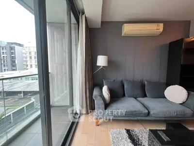 Modern living room with large windows and balcony view in urban apartment.