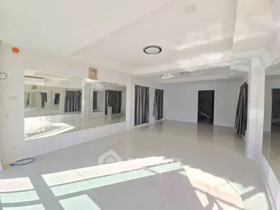 Spacious sunlit living room with large mirrors and modern lighting, perfect for entertaining.