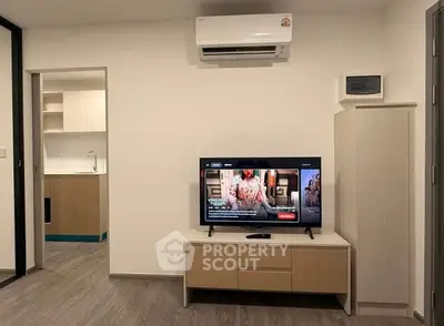 Modern living room with air conditioning and TV, open view to kitchen area.