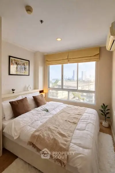 Cozy bedroom with large window offering city views, featuring a comfortable bed and stylish decor.