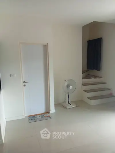 Modern minimalist interior with sleek staircase and fan in bright living space.