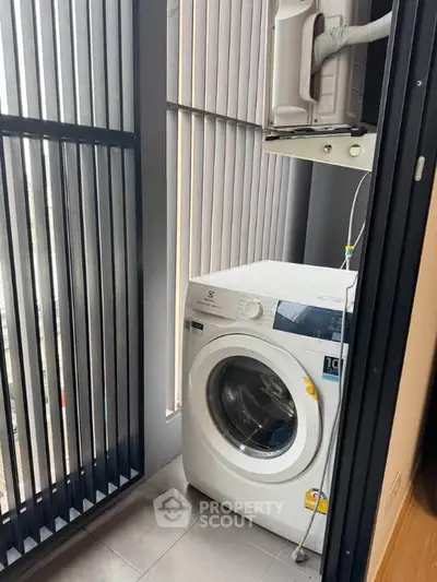 Modern laundry area with washing machine and sleek vertical blinds in a compact space.