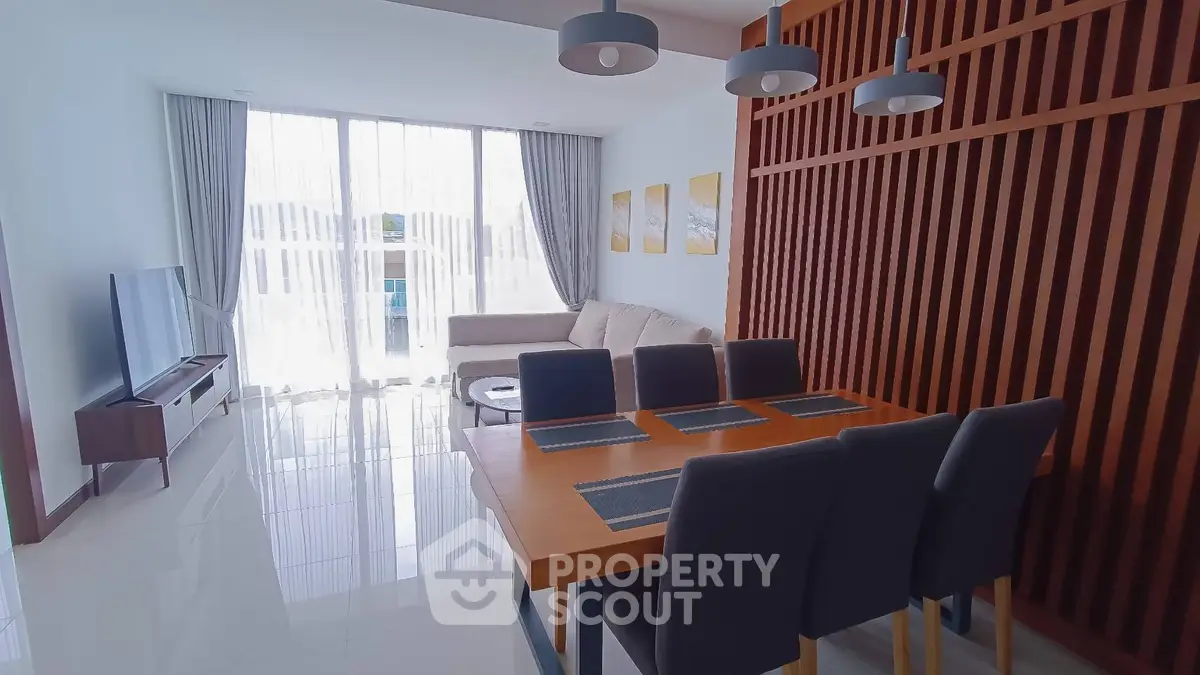 Modern living and dining area with sleek furniture and large windows in a stylish apartment.