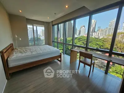 Spacious bedroom with panoramic city view and modern furnishings.