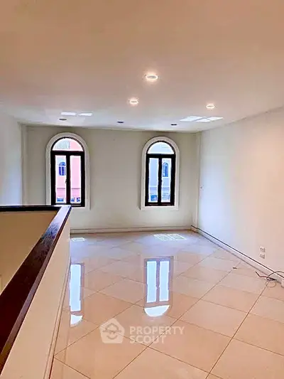 Spacious living room with elegant arched windows and glossy tiled flooring.