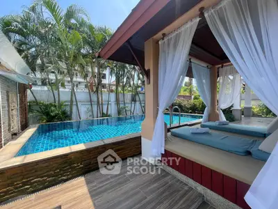 Luxurious poolside cabana with elegant drapes and tropical landscaping, perfect for relaxation and leisure.
