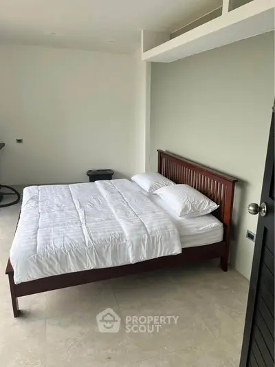 Spacious bedroom with modern wooden bed and minimalist decor, perfect for relaxation.