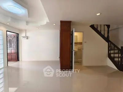 Spacious open-plan living area with elegant staircase and modern tile flooring