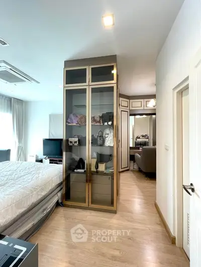 Spacious bedroom with modern decor and ample natural light, featuring a stylish glass wardrobe and cozy seating area.