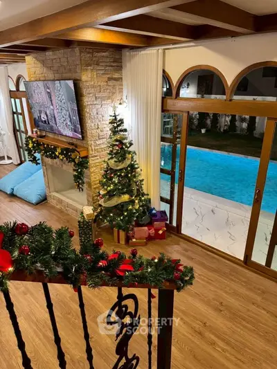 Luxurious living room with pool view, festive decor, and cozy fireplace