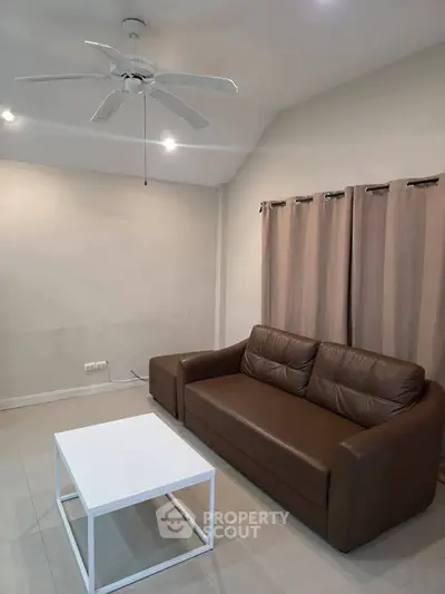 Cozy living room with brown leather sofa and white coffee table, perfect for relaxation.