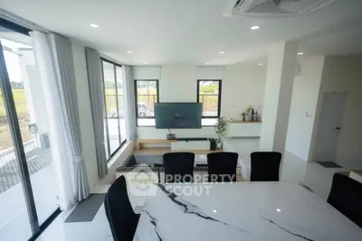 Spacious modern living room with large windows and elegant dining area, perfect for family gatherings.