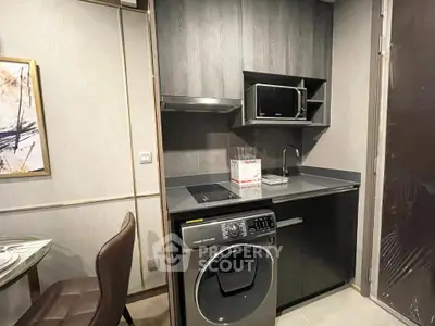 Modern compact kitchen with washing machine and microwave in sleek design.