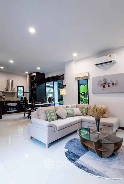 Spacious modern living room with open kitchen, stylish decor, and natural light.