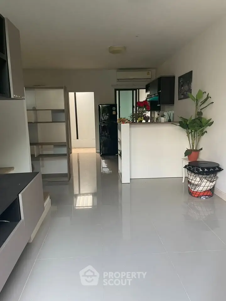 Spacious modern living room with sleek tile flooring and open kitchen layout.