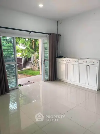 Spacious living room with large windows and garden view, perfect for natural light lovers.