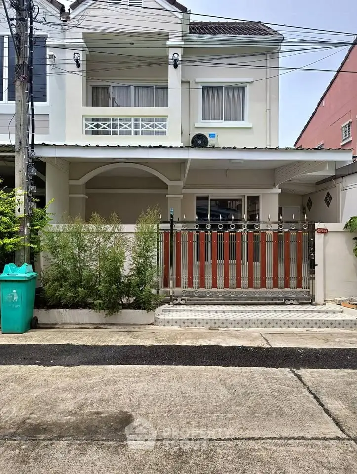 Charming two-story townhouse with gated entrance and lush greenery in a serene neighborhood.