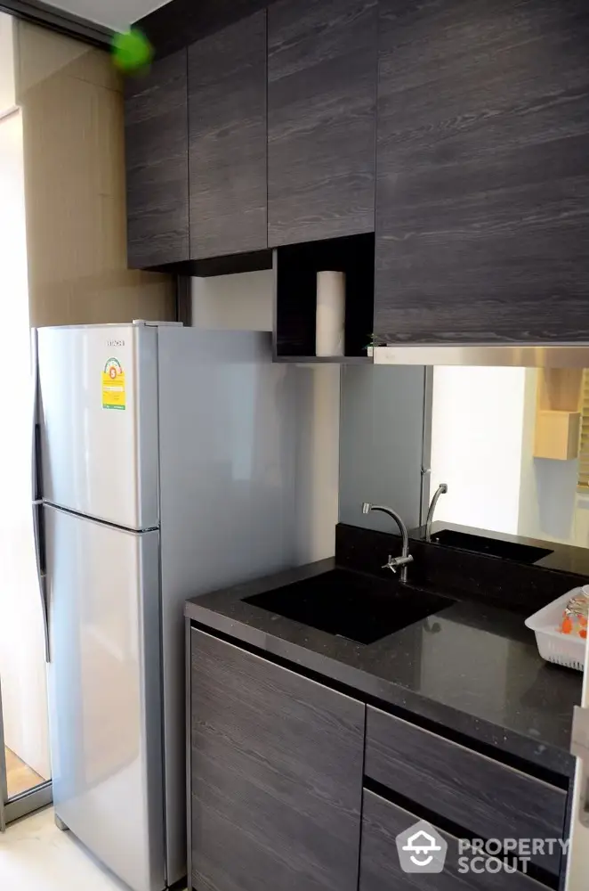 Modern kitchen with sleek dark cabinets and stainless steel fridge