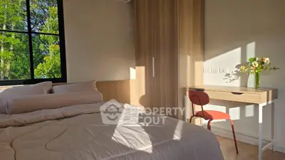 Cozy bedroom with natural light, modern furniture, and a serene view.