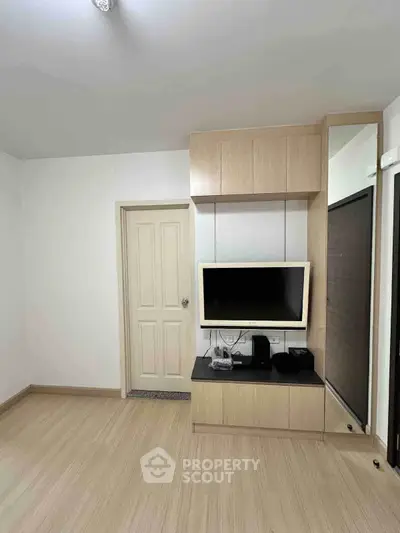 Modern living room with sleek wooden cabinetry and mounted TV, showcasing minimalist design.