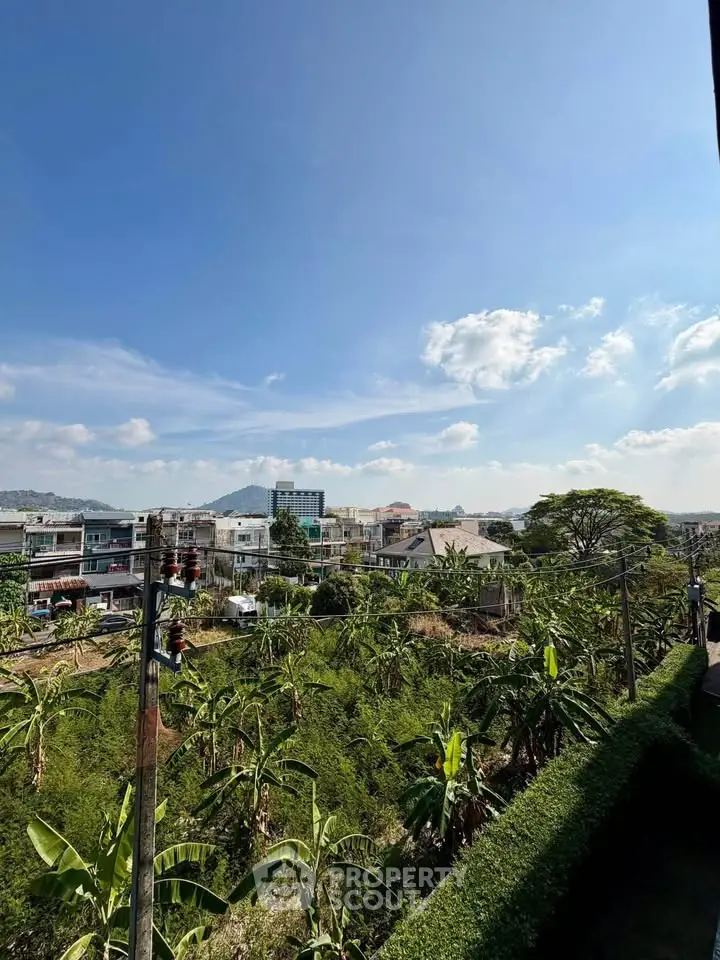 Scenic view of urban landscape with lush greenery and distant mountains under a clear blue sky.