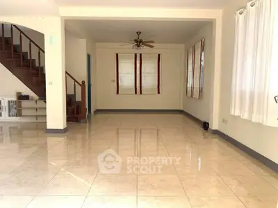 Spacious empty living room with tiled floors and staircase, perfect for customization.