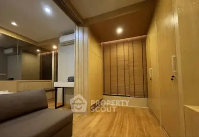 Modern living room with wooden flooring and stylish blinds, featuring a cozy sofa and air conditioning.