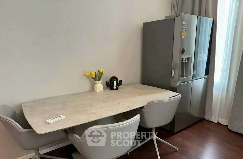 Modern dining area with sleek table, stylish chairs, and stainless steel fridge