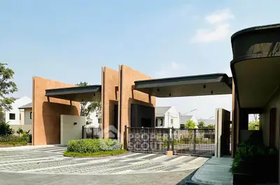 Modern gated entrance of a residential community with contemporary design and lush greenery.