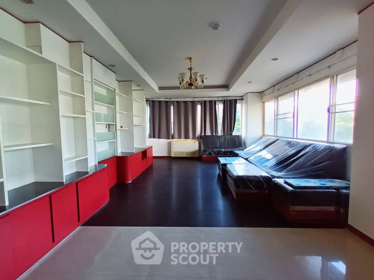 Spacious living room with modern red and white built-in shelves and large windows.