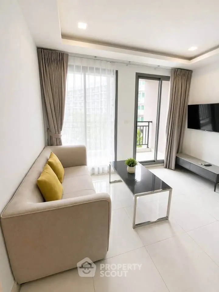 Modern living room with sleek furniture and large window offering natural light and balcony access.