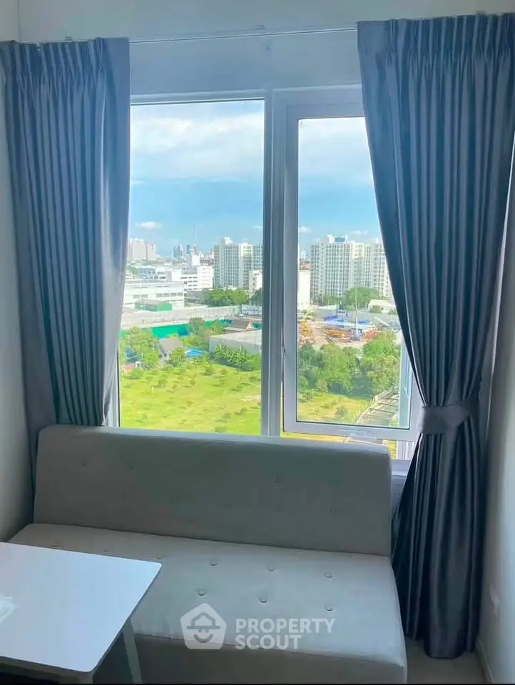Cozy living room with a stunning city view through large windows, perfect for relaxation.