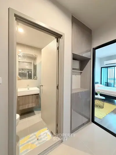 Modern apartment interior with bathroom and bedroom view, featuring sleek cabinetry and contemporary design.