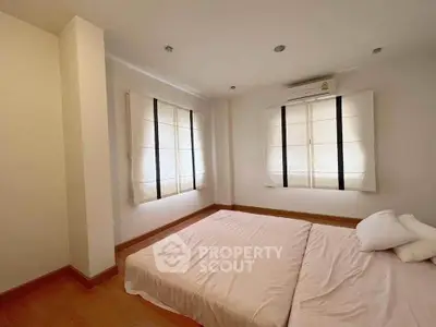 Spacious bedroom with large windows and minimalist decor in modern apartment.