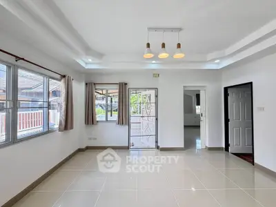 Spacious living room with modern lighting and large windows in a bright, airy home.