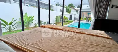 Luxurious bedroom with pool view in modern villa, large windows enhance natural light.