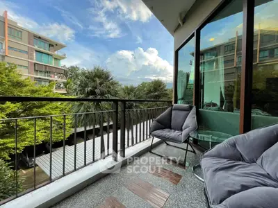 Charming balcony with cozy seating and lush views in modern apartment complex.