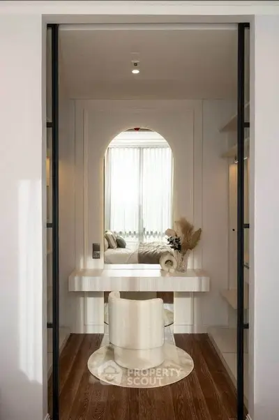 Elegant bedroom with modern vanity and plush chair, featuring soft lighting and stylish decor.