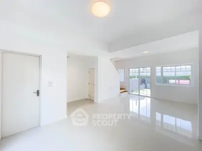 Spacious and bright living room with large windows and glossy floors in modern home.