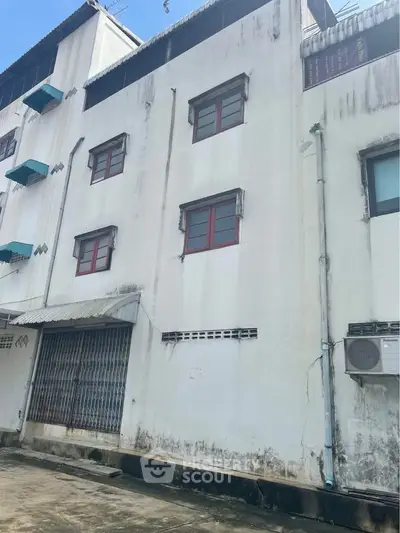 Exterior view of a multi-story building with air conditioning unit and metal awning.