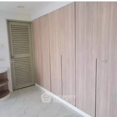 Spacious modern storage area with sleek wooden cabinets and elegant marble flooring.