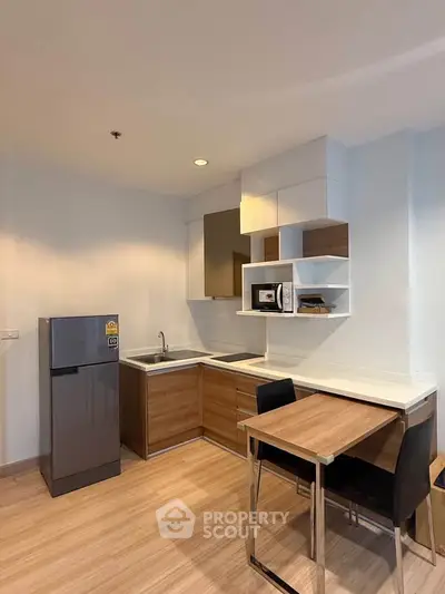 Modern kitchen with sleek wooden cabinets and dining area in a stylish apartment.