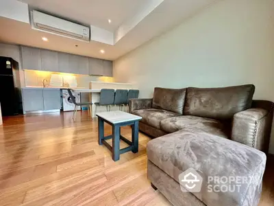 Spacious open-plan living room with plush sofa set and modern kitchen featuring under-cabinet lighting and sleek appliances.