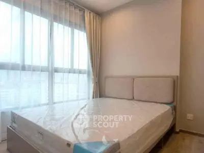 Bright and airy bedroom with large window and modern furnishings, perfect for a cozy retreat.