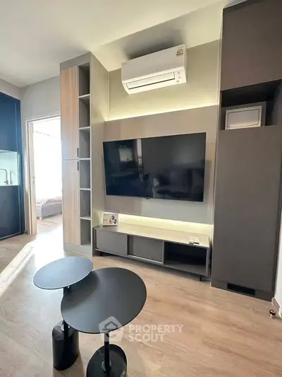 Modern living room with sleek furniture and large TV, featuring stylish built-in storage and air conditioning.