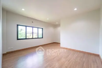 Spacious empty room with wooden flooring and large window