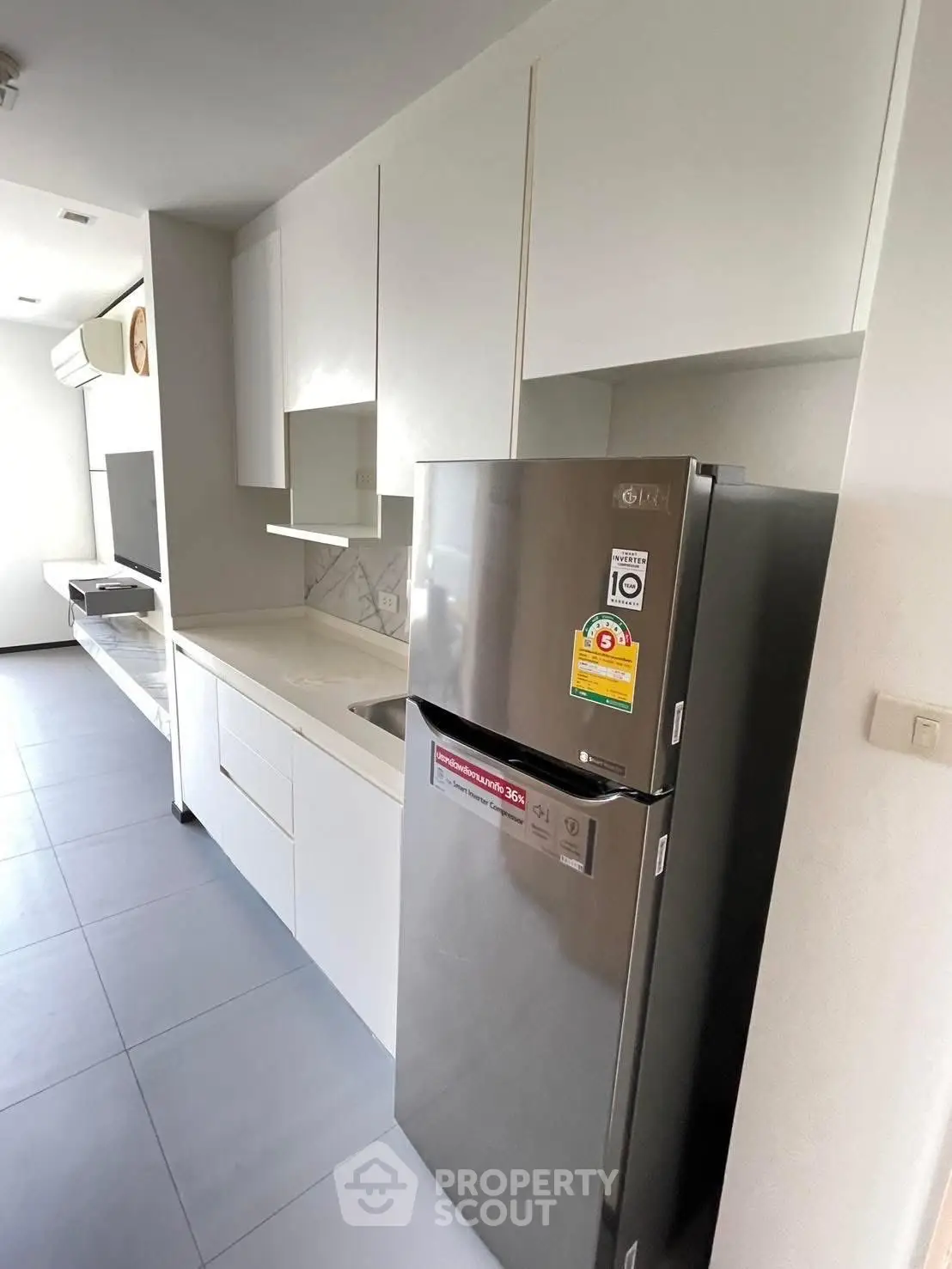 Modern kitchen with sleek white cabinets and stainless steel fridge in a stylish apartment.