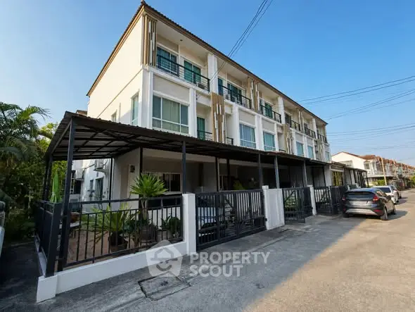 Modern three-story townhouse with gated entrance and driveway in a suburban neighborhood.
