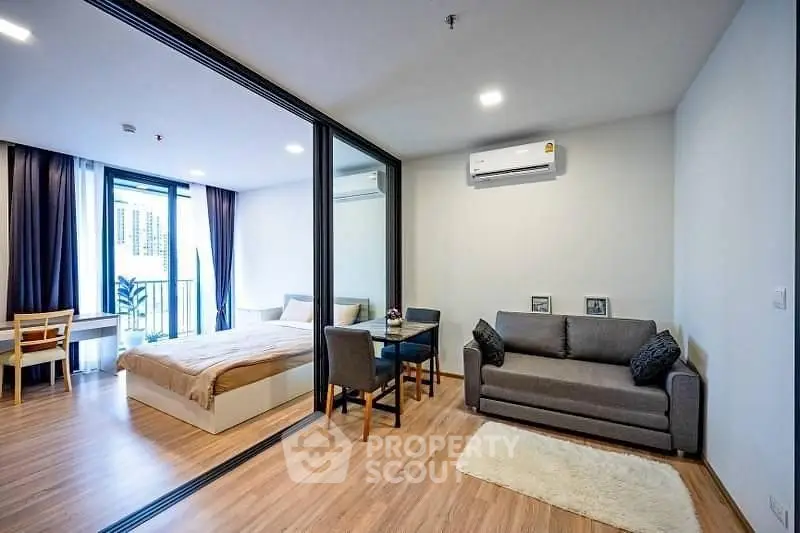 Modern studio apartment with open layout, featuring a cozy living area and bedroom with large windows.