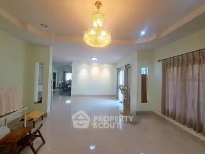 Spacious living room with elegant chandelier and large windows for natural light.